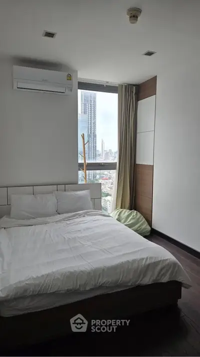 Modern bedroom with city view, featuring a cozy bed and air conditioning, perfect for urban living.