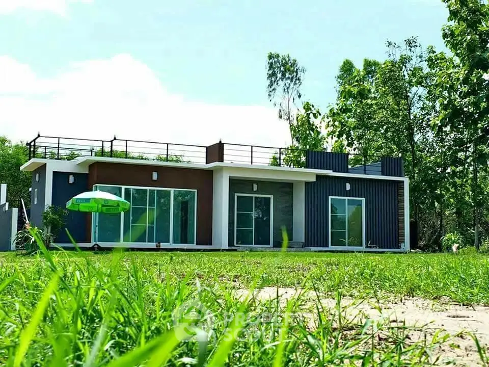 Modern single-story house with lush green surroundings and rooftop terrace.