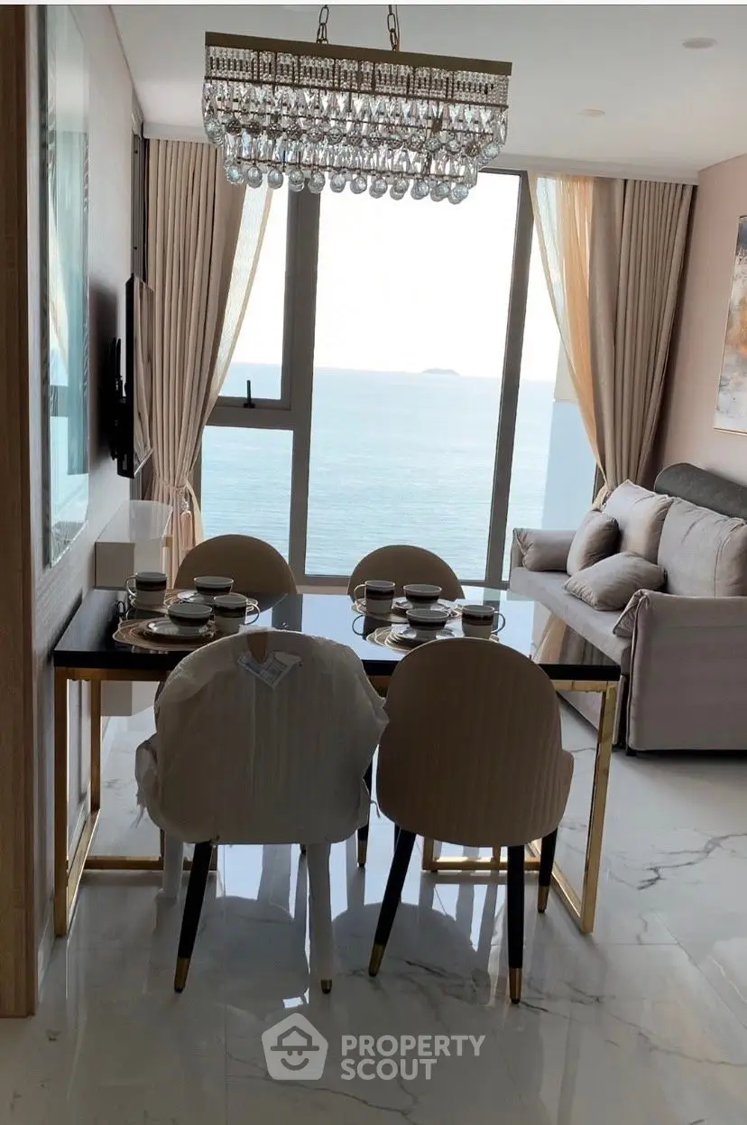 Luxurious dining area with ocean view, elegant chandelier, and modern decor.