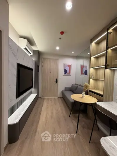 Modern living room with sleek design, featuring a wall-mounted TV, stylish furniture, and elegant lighting.