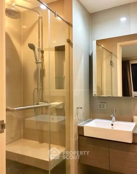 Modern bathroom with glass shower and sleek vanity in contemporary apartment.