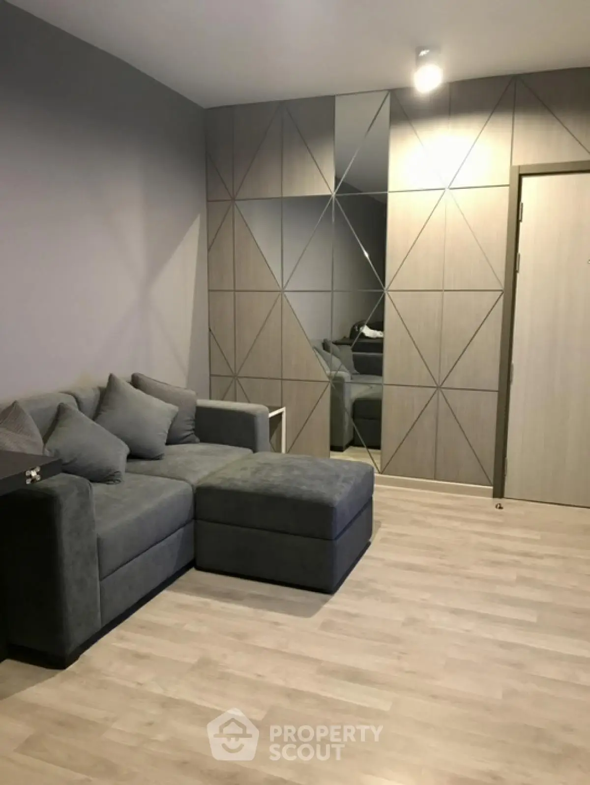 Modern living room with stylish geometric wall design and cozy grey sofa