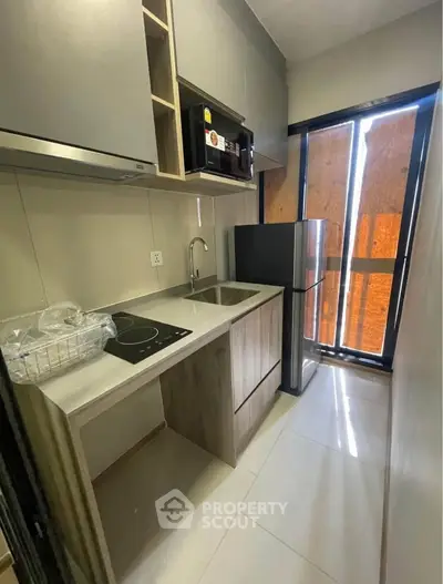 Modern compact kitchen with sleek appliances and ample storage in a stylish apartment.