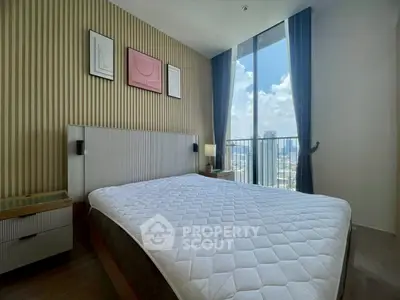 Modern bedroom with large window offering stunning city views and stylish decor.