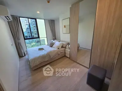 Modern bedroom with large window and mirrored wardrobe in a stylish apartment.