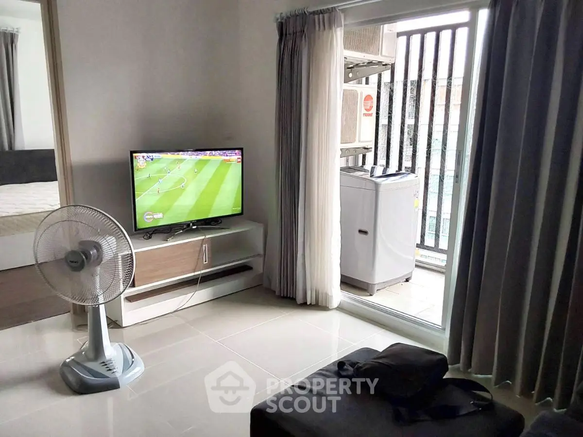Modern living room with TV, fan, and balcony view in stylish apartment.