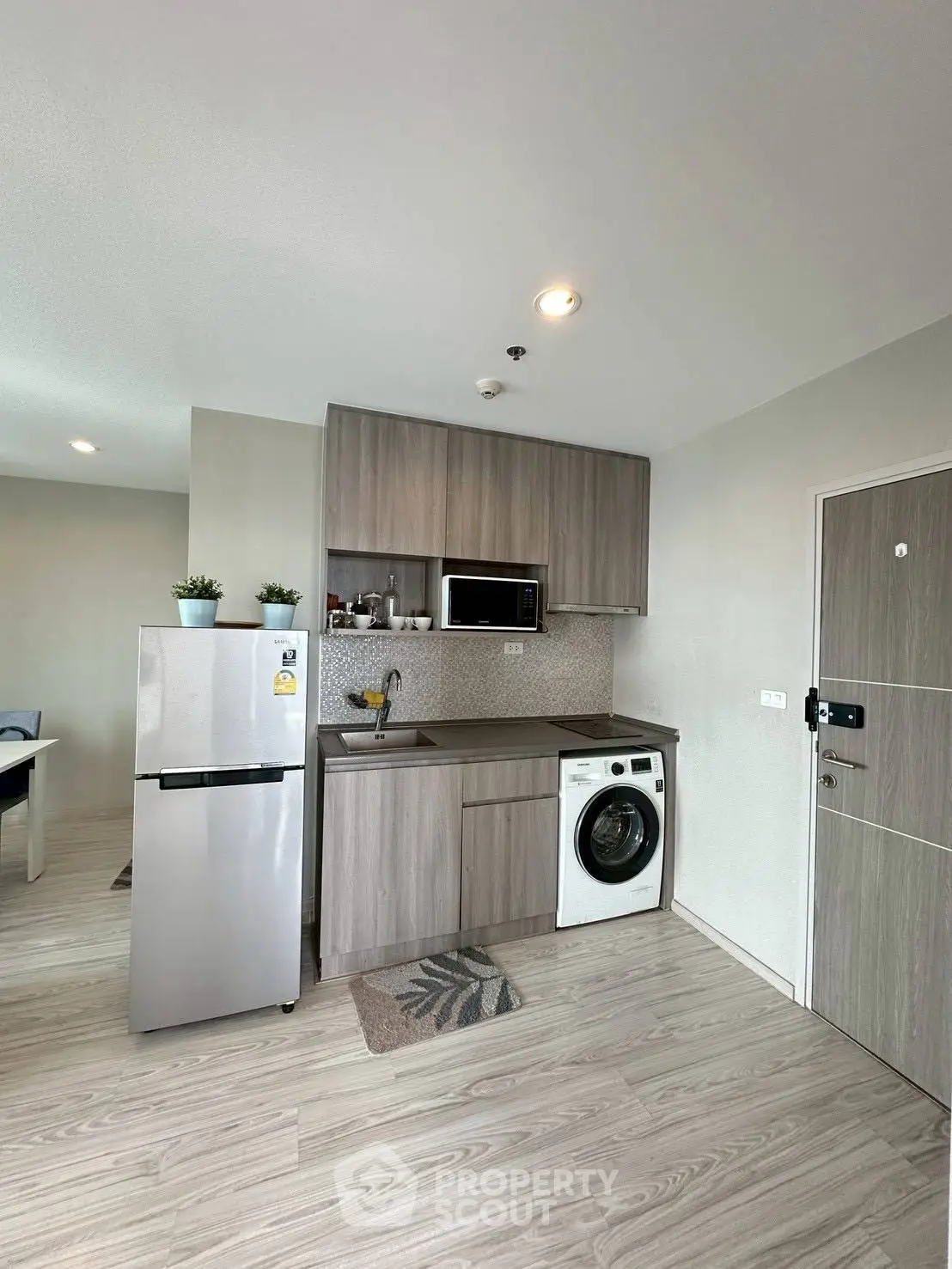 Modern kitchen with sleek cabinets, stainless steel fridge, and built-in washing machine in stylish apartment.