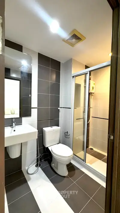 Modern bathroom with sleek design, featuring a shower enclosure and stylish tiles.