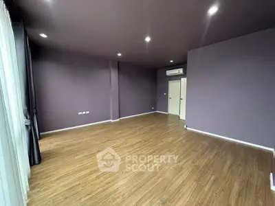 Spacious empty room with wooden flooring and modern lighting, ideal for customization.