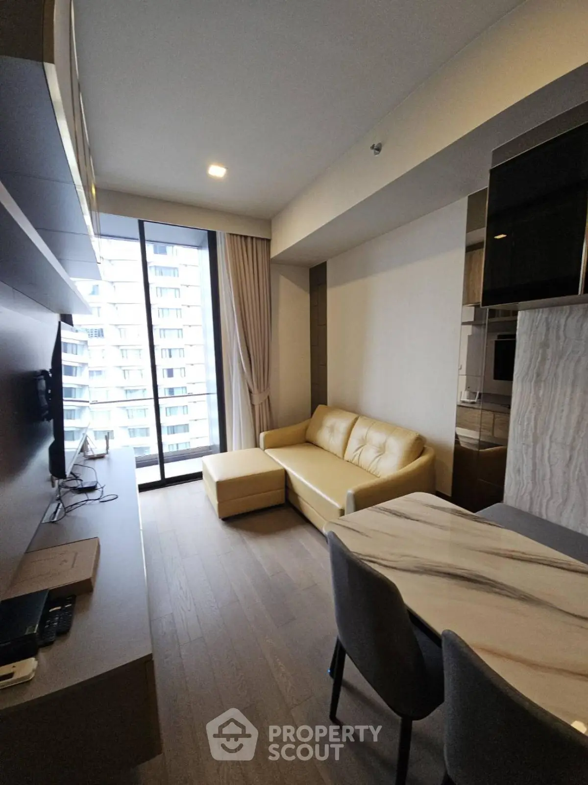 Modern living room with stylish furniture and large window offering city view in a high-rise apartment.