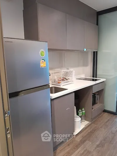 Modern compact kitchen with sleek cabinetry and stainless steel fridge
