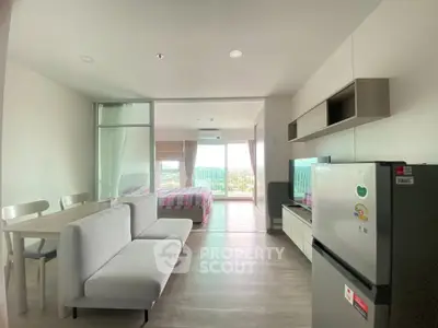 Modern open-plan living room with dining area and bedroom, featuring large windows and natural light.
