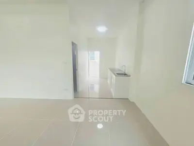 Minimalist kitchen area with sleek tile flooring and compact sink unit.