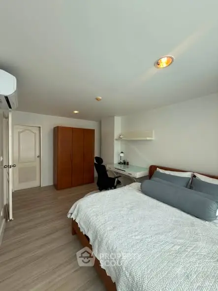 Spacious bedroom with modern decor and ample natural light, featuring a cozy bed and stylish furniture.