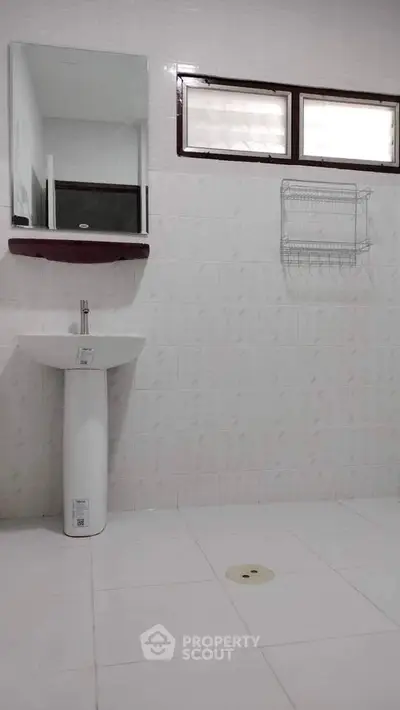 Spacious bathroom with pedestal sink and wall-mounted storage