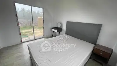 Minimalist bedroom with large window and simple furnishings