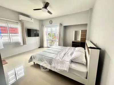Spacious bedroom with modern decor, featuring a large bed, wall-mounted TV, and ample natural light.