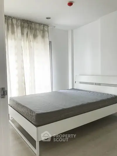 Minimalist bedroom with white bed frame and large window, perfect for modern living.
