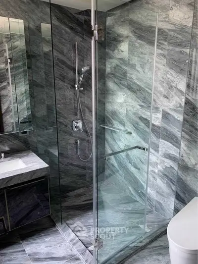 Luxurious modern bathroom with sleek glass shower and elegant marble tiles.