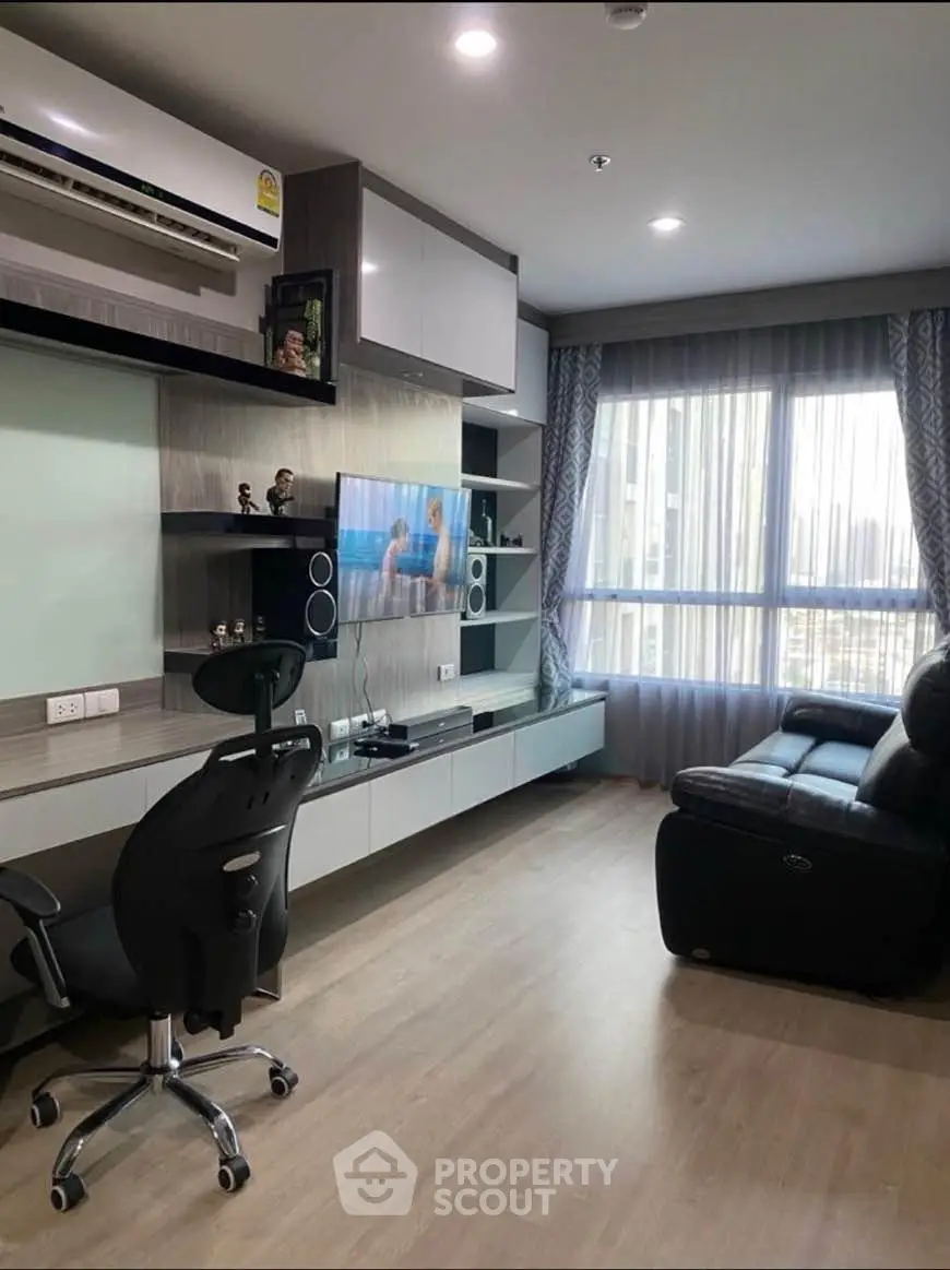 Modern living room with sleek furniture and large window offering natural light.
