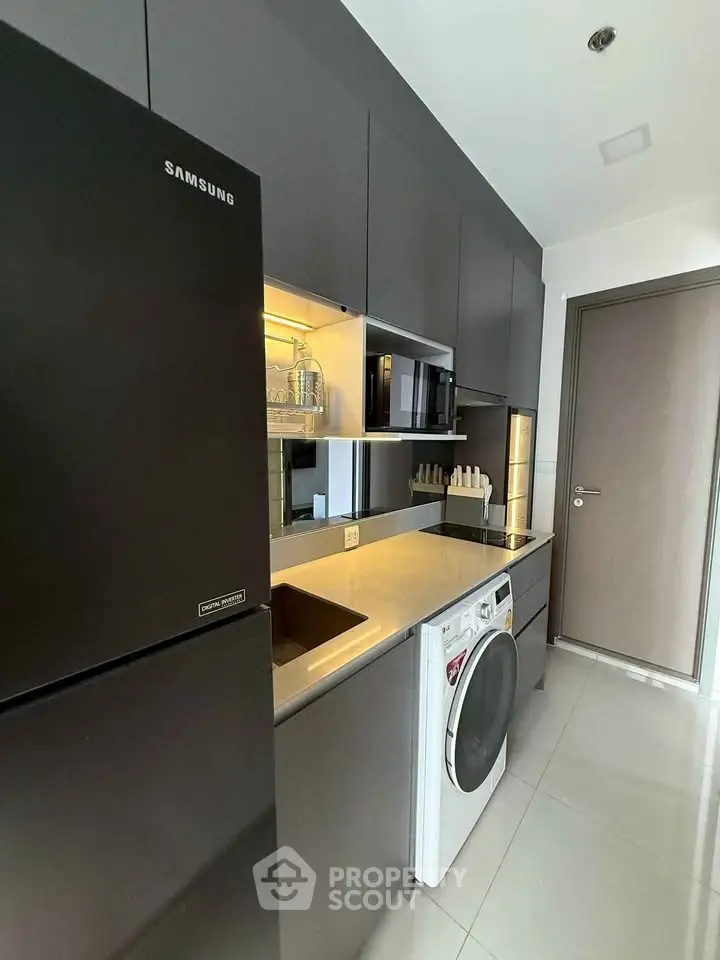 Modern kitchen with sleek cabinetry, washing machine, and built-in appliances in a compact layout.