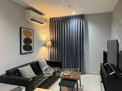 Modern living room with sleek black leather sofa, stylish decor, and ambient lighting.