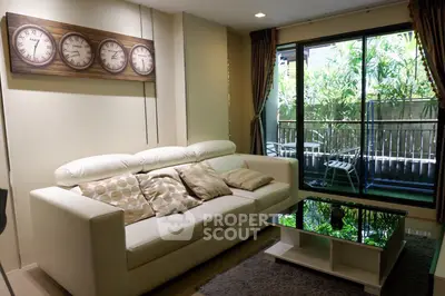 Modern living room with white sofa and glass coffee table, overlooking a lush balcony view.