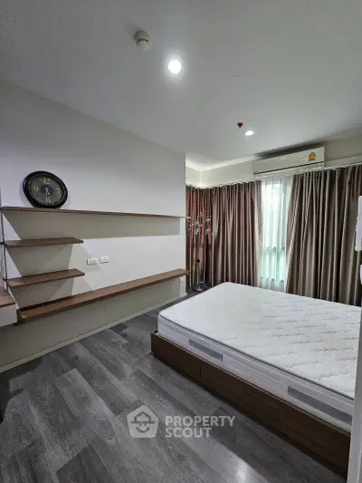 Modern bedroom with stylish decor and ample natural light, featuring a comfortable bed and sleek wooden flooring.