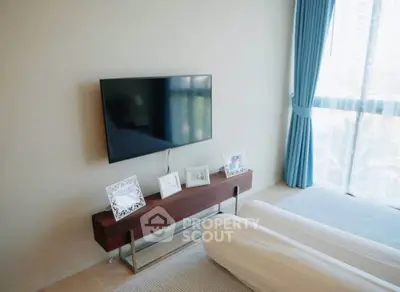 Modern bedroom with wall-mounted TV and large window with blue curtains.
