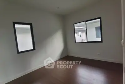 Spacious empty room with wooden flooring and large windows for natural light.