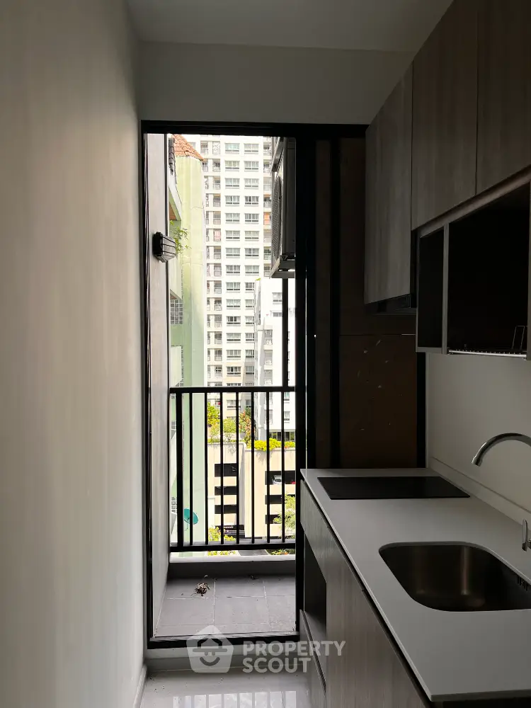 Modern kitchen with sleek cabinetry and balcony view in urban apartment