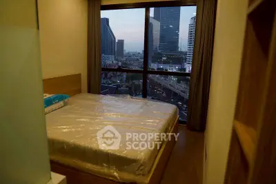 Cozy bedroom with city view from large window in modern apartment