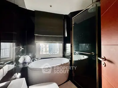 Luxurious modern bathroom with city view, featuring sleek black tiles and a stylish bathtub.