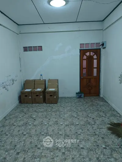 Unfurnished room with tiled floor and wooden door, ideal for storage or renovation.