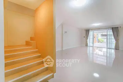 Spacious modern living room with elegant staircase and large windows for natural light.