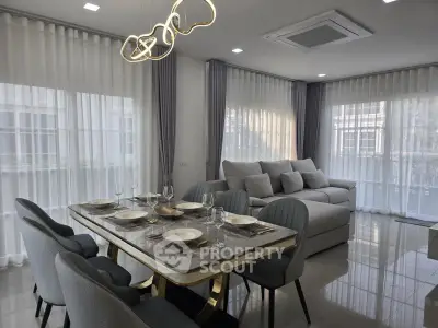Elegant modern living room with dining area, featuring stylish furniture and large windows.