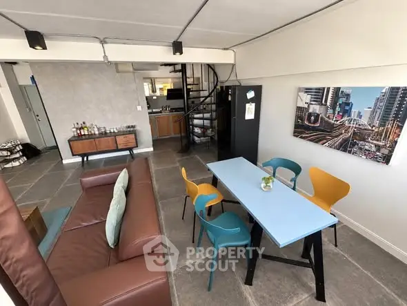Modern open-plan living room with stylish furniture and spiral staircase in urban apartment.