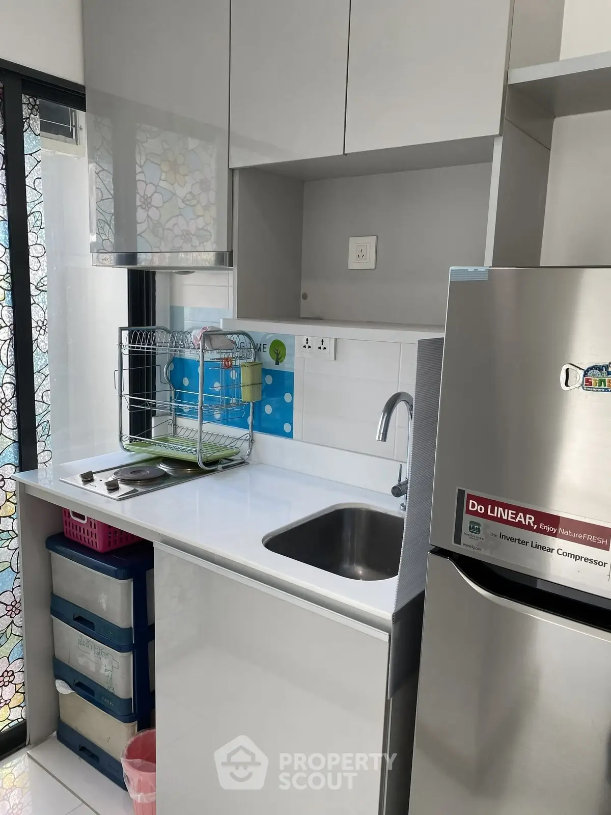 Modern compact kitchen with sleek cabinetry and stainless steel fridge, perfect for urban living.