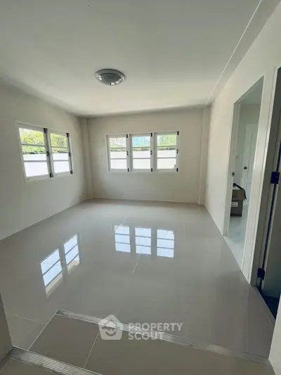Spacious unfurnished room with large windows and glossy tiled floor, perfect for customization.