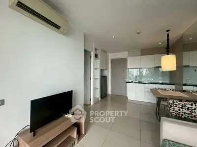 Modern open-layout living room with kitchen and dining area, featuring sleek design and ample natural light.