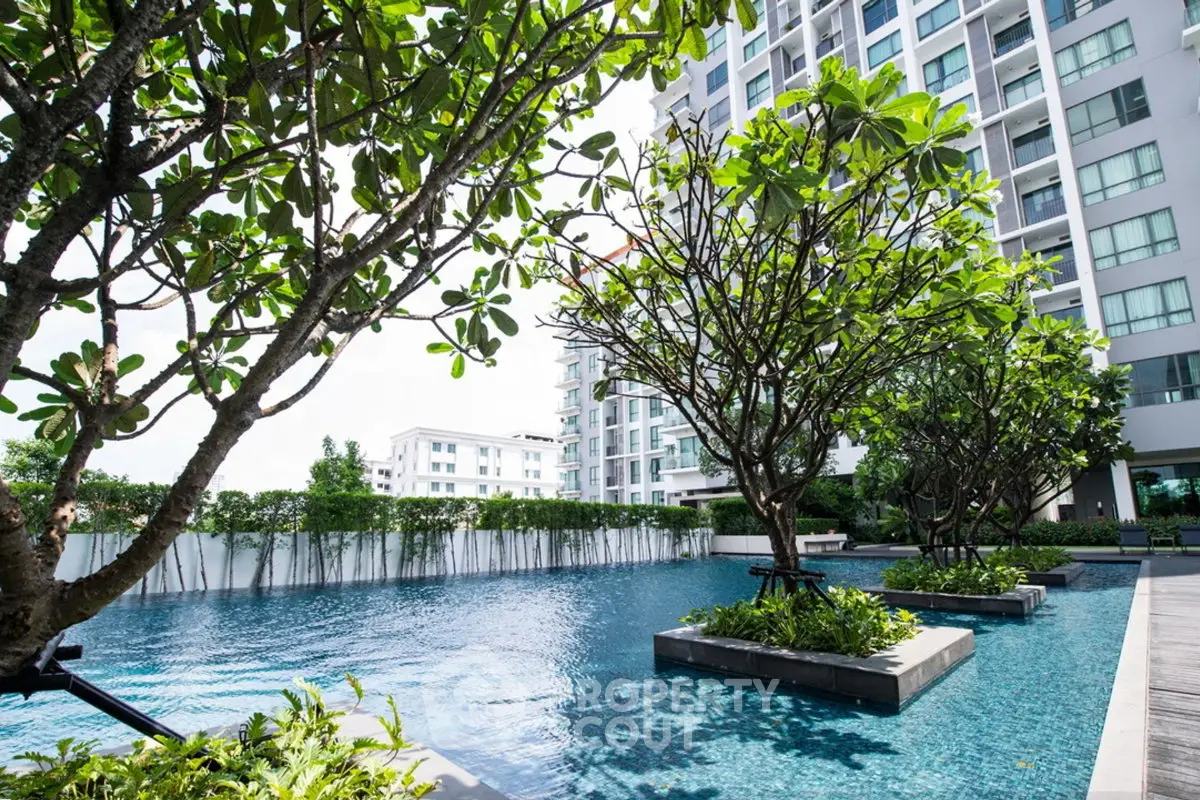 Luxurious apartment complex with serene pool and lush greenery, perfect for relaxation and modern living.