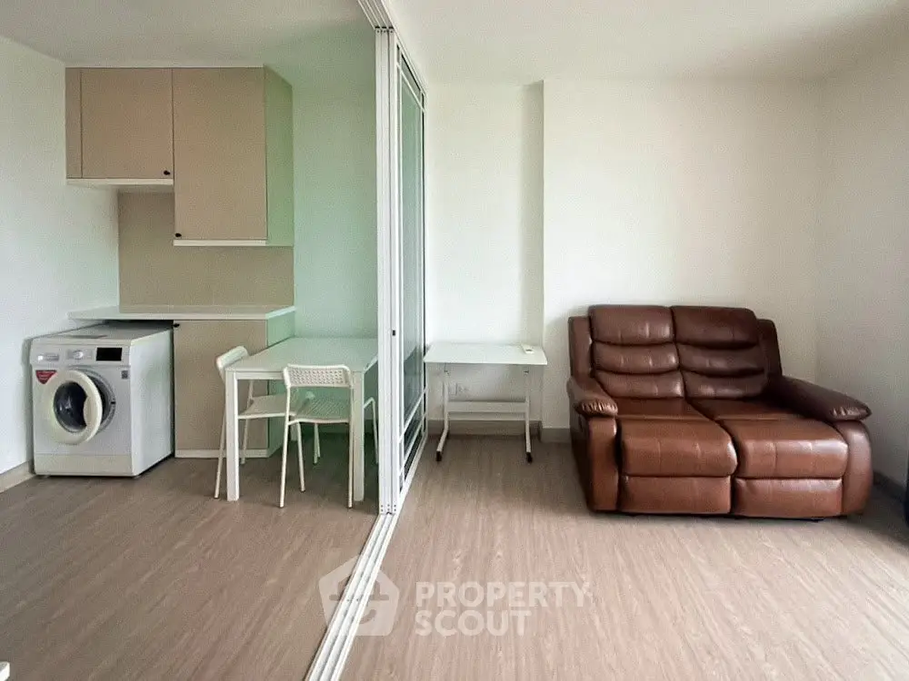 Modern living room with washing machine and brown leather sofa, perfect for urban living.