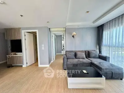 Spacious modern living room with large windows and stylish gray sectional sofa.