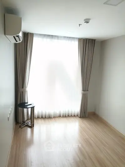 Bright and airy empty room with large window and wooden flooring, perfect for customization.
