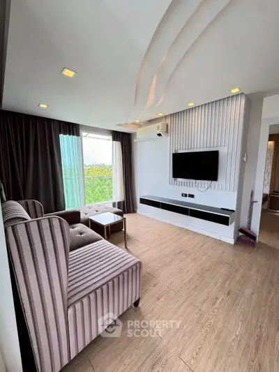 Stylish modern living room with elegant furniture and wall-mounted TV, featuring large windows and natural light.