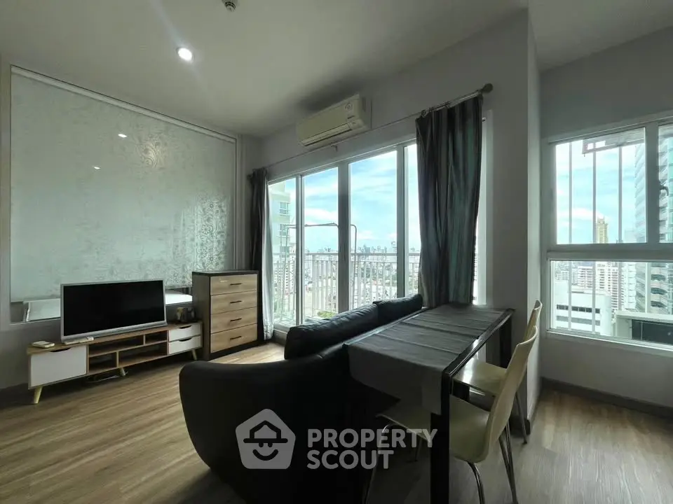 Modern living room with city view, featuring sleek furniture and large windows for natural light.
