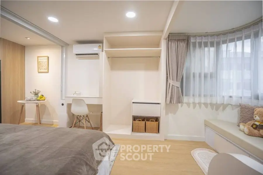 Modern bedroom with study area and cozy decor, featuring natural light and stylish furnishings.