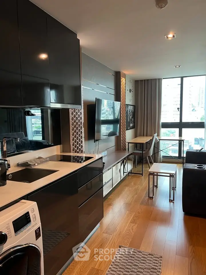 Modern open-layout kitchen and living area with sleek black cabinets and city view.
