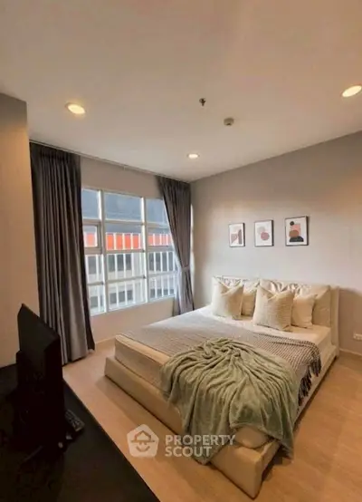 Spacious bedroom with modern decor and large windows in a stylish apartment.