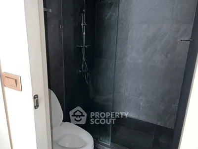 Modern bathroom with sleek dark tiles and glass shower enclosure